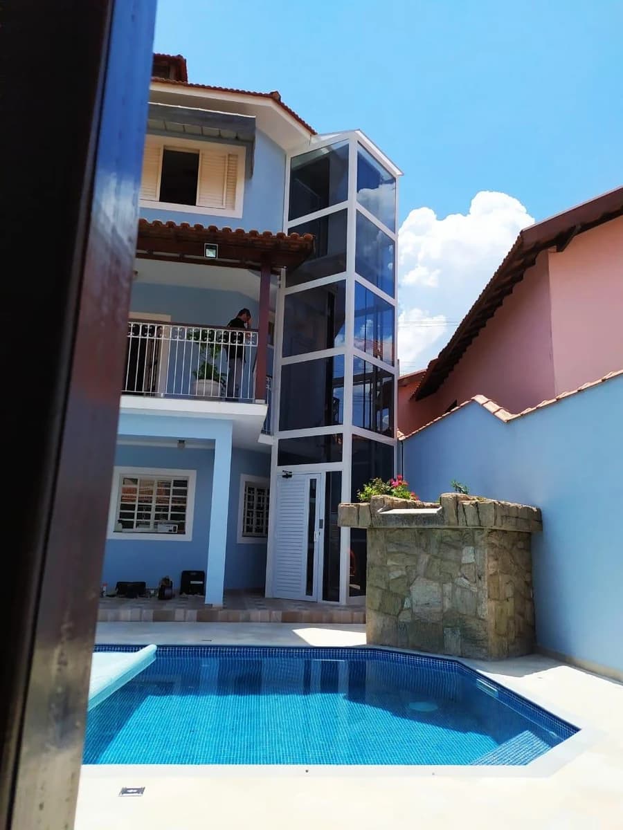 Elevador residencial panorâmico de vidro instalado em área externa.