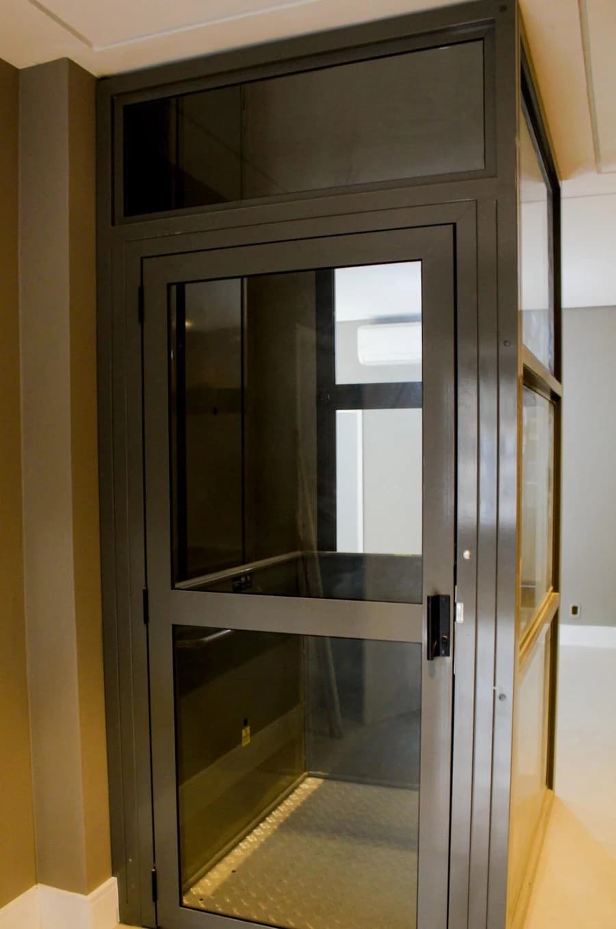 Elevador de passageiros instalado com cabine e porta de vidro.